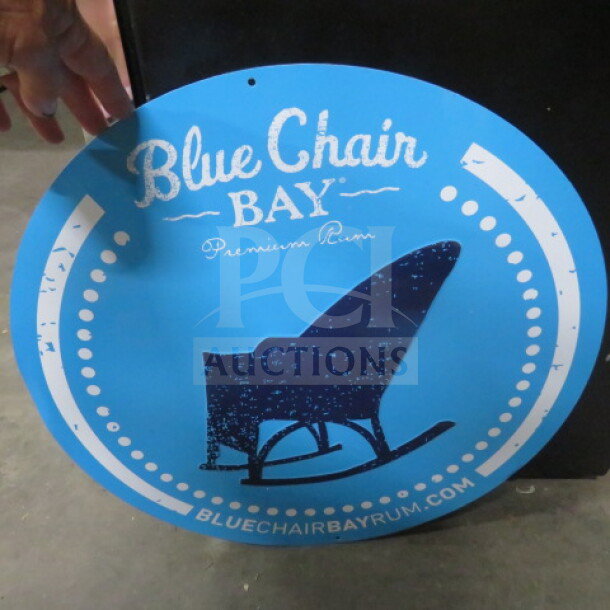 Round 20-inch Blue Chair Bay tin sign, blue with white text and rocking chair graphic, good condition.