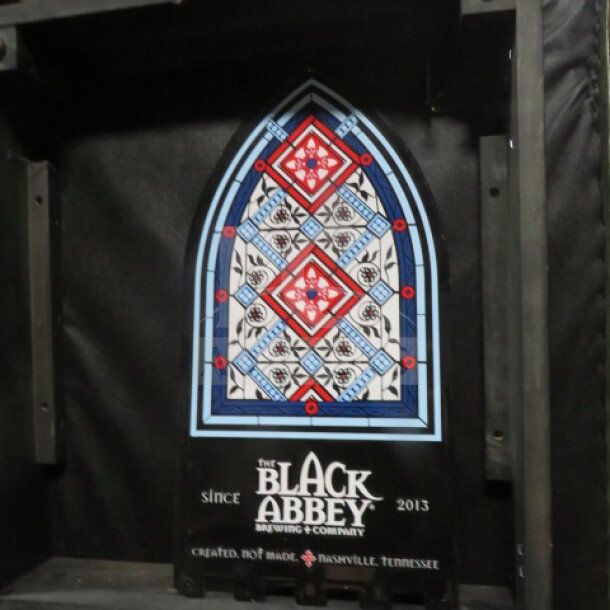 11.5x22.5-inch Black Abbey tin sign with stained glass design and branding, excellent condition.