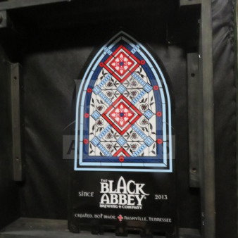 11.5x22.5-inch Black Abbey tin sign with stained glass design and branding, excellent condition.