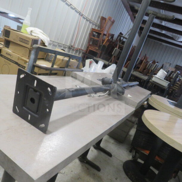 Black metal TV mount pole, wall-mount style with adjustable arm. Moderate wear, visible in storage setting.