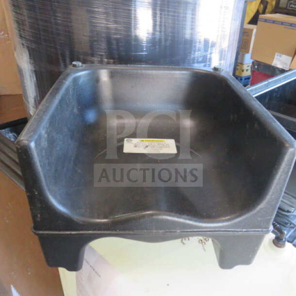 Dual-sided black booster seat, durable plastic, slight wear. White safety label on seat base.
