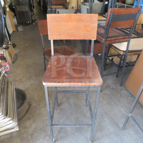 Black metal bar height chair with brown wooden seat and back, used condition. Simple, industrial design.