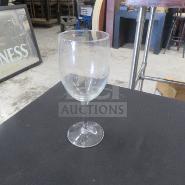 Clear stem wine glass, gently used, 10XBID model, standing on a black surface in an industrial setting.
