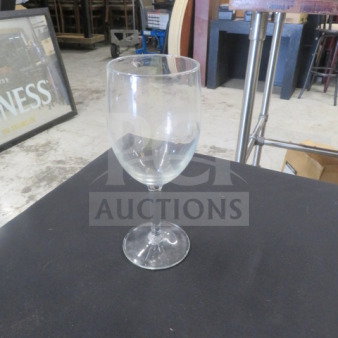 Clear stem wine glass, gently used, 10XBID model, standing on a black surface in an industrial setting.