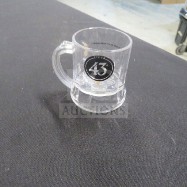 Clear plastic shot glass with "Licor 43" logo, handle, and durable construction. Appears in excellent condition.