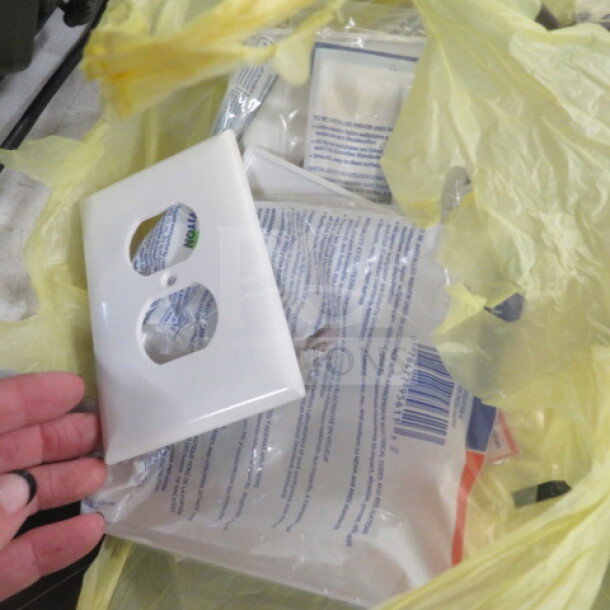 New assorted electrical outlet plates in original packaging, in a yellow plastic bag. White finish, standard dual outlet design.