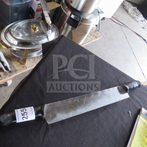 Double handle knife with long blade, black grip handles, tag labeled "255", placed on a black table cloth.