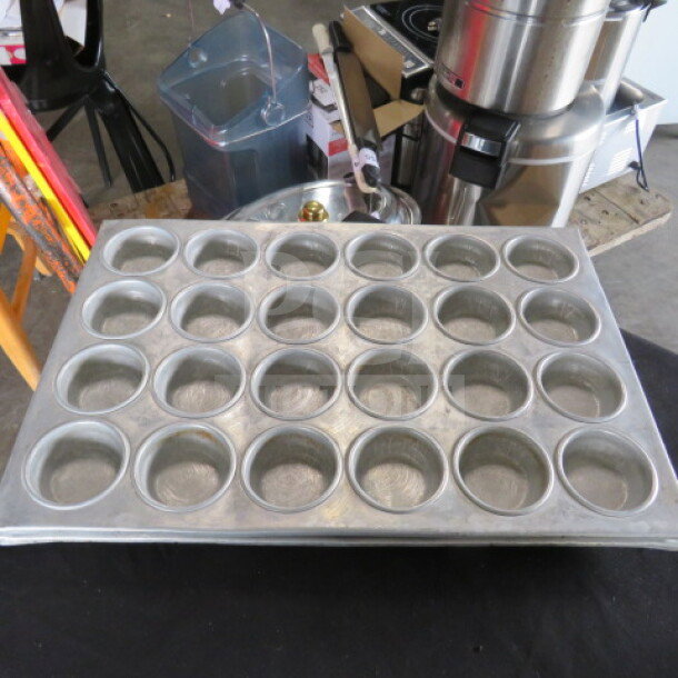 24-hole commercial muffin pan, durable metal, slightly worn, ideal for bakery use. Model 2XBID visible on rim.