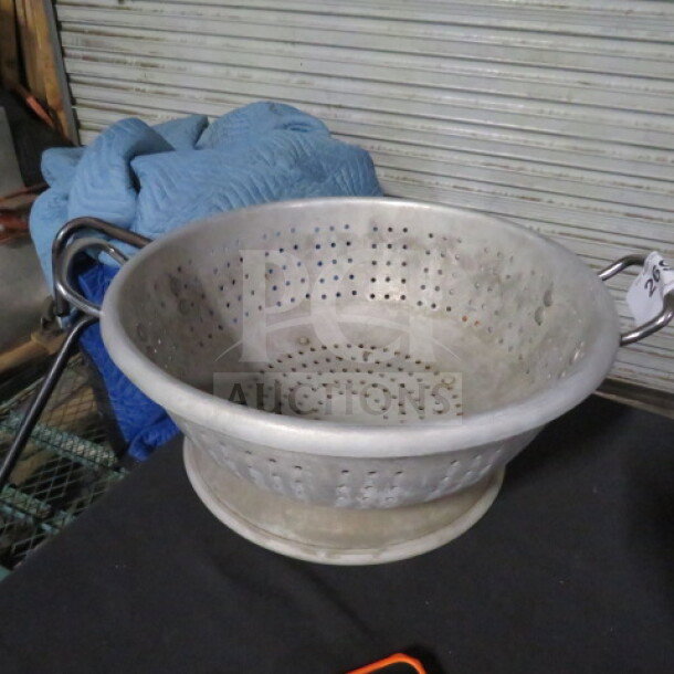 15.5-inch aluminum colander with perforated design, sturdy handles, used condition; auction tag visible.