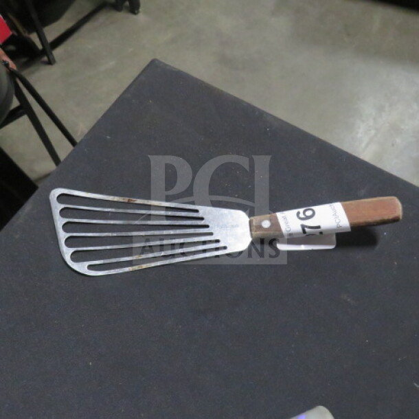 Stainless steel fish turner with wooden handle, slight rust on metal, auction tag 76 attached.