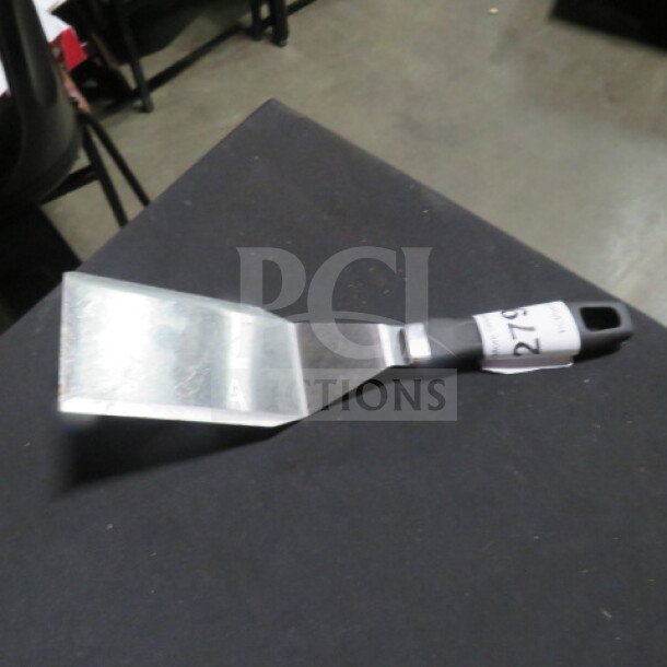 Stainless steel hamburger turner with black handle, appears in good condition, features a price tag with the number 279.
