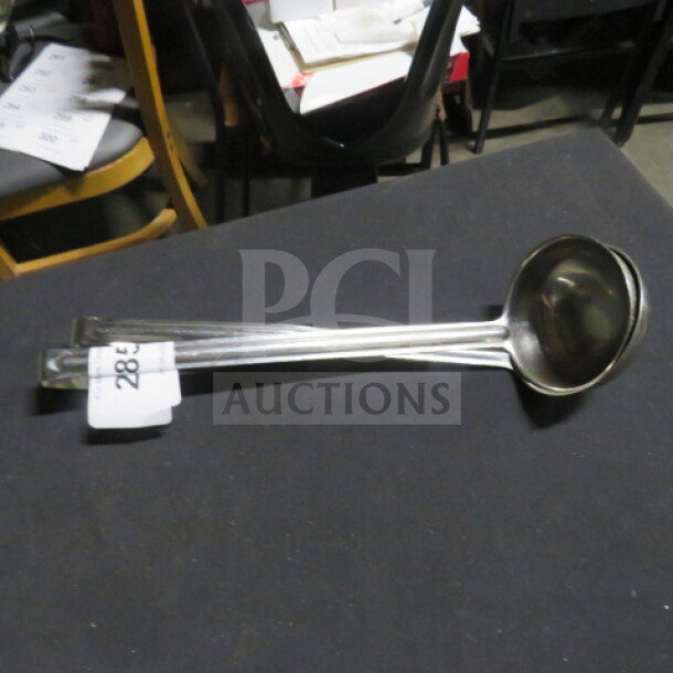 8oz stainless steel ladle with long handle, used condition. Visible tag marked "28" indicating auction lot.