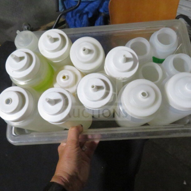 A lot of assorted squeeze bottles in a plastic container, white caps, various sizes, appears in used but good condition.