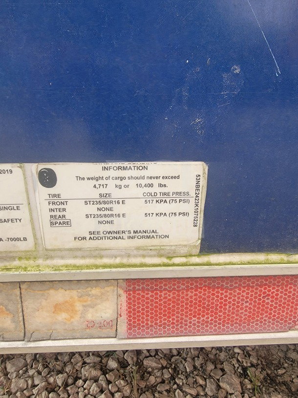 Blue trailer with a label indicating a cargo weight limit of 10,400 lbs. Tire size ST235/80R16 E, pressure 75 PSI.
