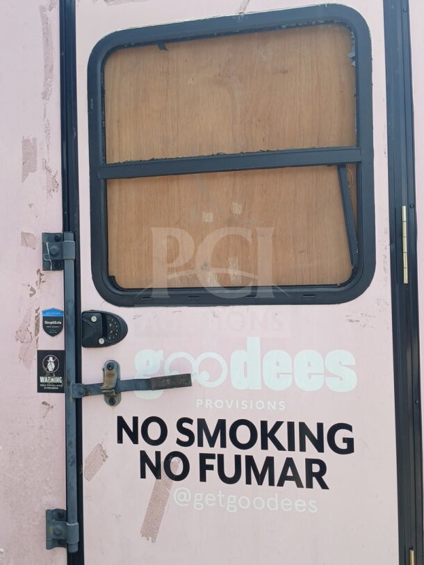 Mobile infrastructure trailer door with "No Smoking, No Fumar" text. SimpleSafe and warning stickers visible.