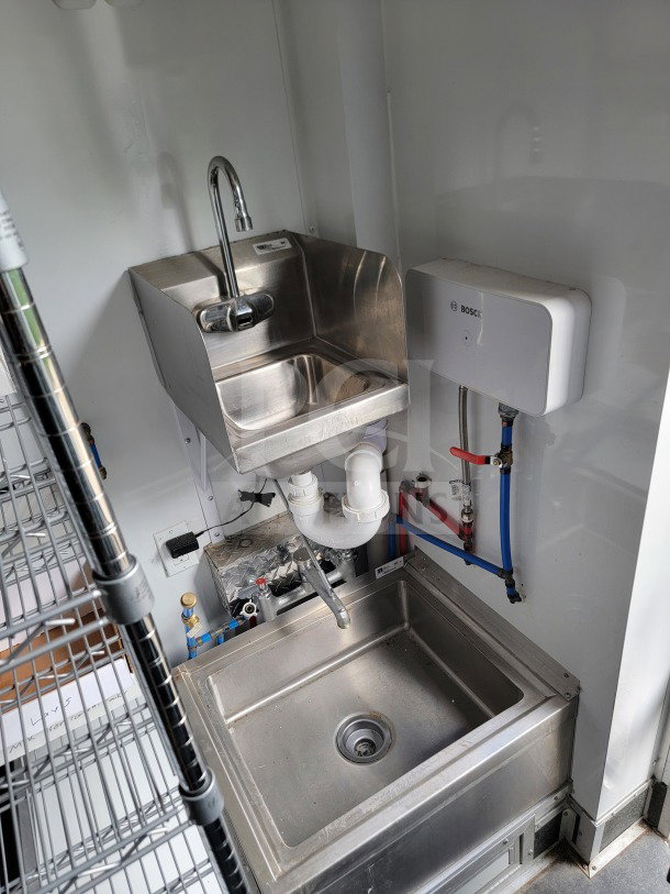 Stainless steel sink area inside 2021 SDG 8.5' x 20' mobile trailer with plumbing and Bosch water heater visible.