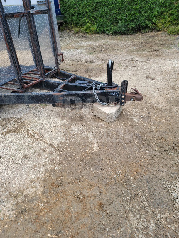 Trailer hitch of 2021 Diamond Cargo 8.5' x 24' mobile kitchen, resting on concrete block, with visible chains and wear marks.