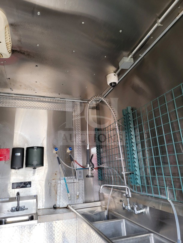 Interior of a 2021 Diamond Cargo mobile kitchen trailer, featuring sinks, sprayers, and mounted accessories in stainless steel.