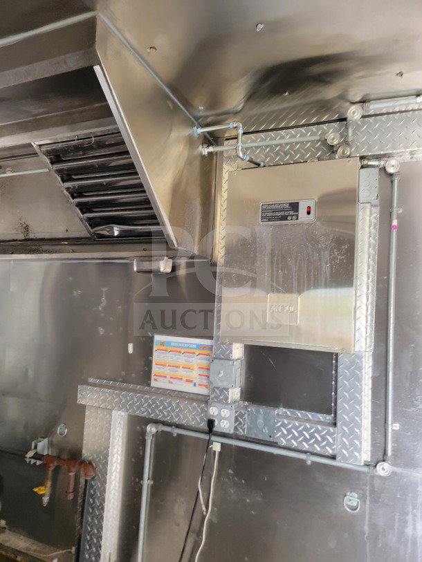 Interior view of 2021 Diamond Cargo 8.5' x 24' mobile kitchen trailer. Features NAKS hood, diamond plate panels, menu description sheet.