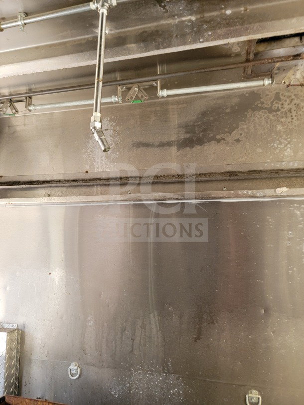 Interior view of the Diamond Cargo mobile kitchen trailer, showing stainless steel walls and ceiling with visible piping.