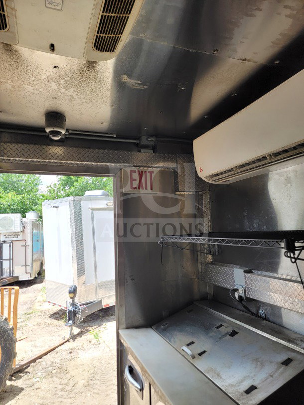 Interior of 2021 Diamond Cargo mobile kitchen trailer, showing industrial shelf, ventilation system, and exit sign.