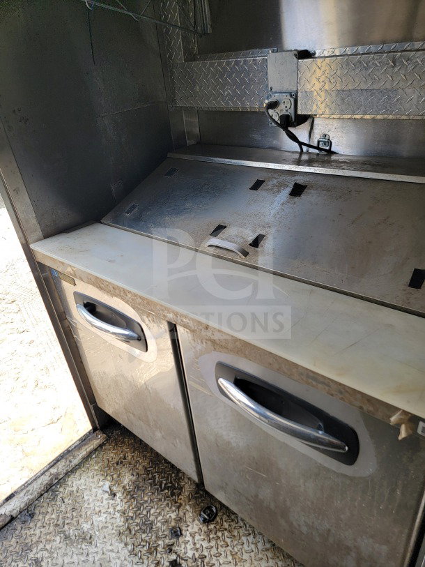 2021 Diamond Cargo mobile kitchen trailer interior, featuring stainless steel surfaces and storage cabinets.