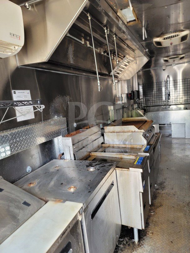 Interior of 2021 Diamond Cargo mobile kitchen trailer showing NAKS hood, Pitco fryers, and stainless steel surfaces.