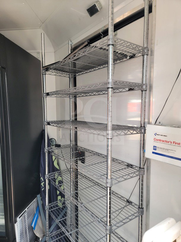 Metal shelving inside 2021 SDG 8.5' x 20' dual-axle mobile kitchen trailer, featuring storage and first aid kit.