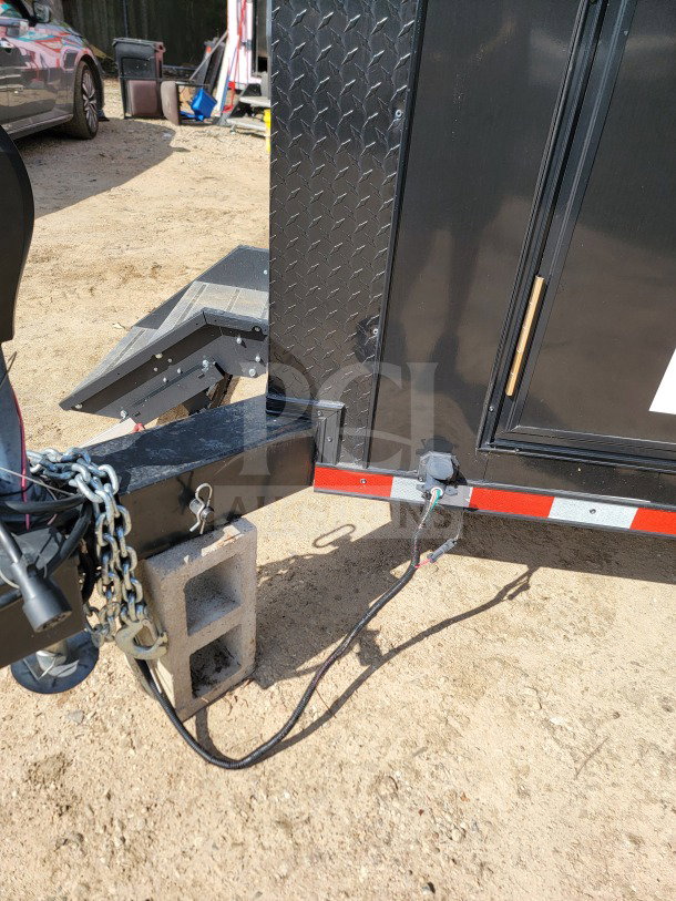 Alt text: SDG 8.5' x 20' mobile kitchen trailer hitch with electrical connections on a dirt surface.
