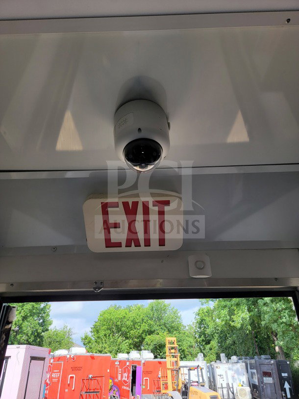 Interior view of 2021 SDG 8.5' x 20' mobile kitchen trailer. Visible exit sign, ceiling camera, outdoor equipment in view.