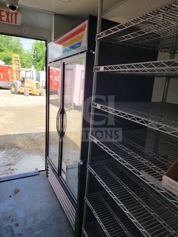 Mobile kitchen trailer interior featuring True Refrigeration unit and metal shelving, part of a 2021 SDG 8.5' x 20' model.