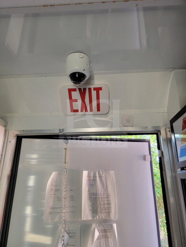 Interior view of SDG Model 20 trailer showing an exit sign, security camera, and documents on a whiteboard.