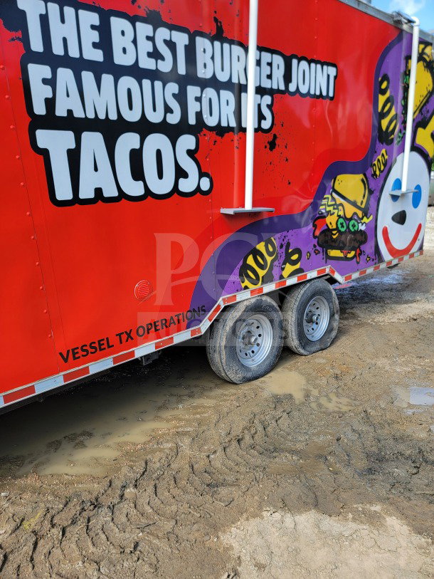 2021 Rock Solid Cargo 8.5' x 24' dual-axle mobile kitchen trailer, vibrant graphics, CaptiveAire hood, in muddy terrain.