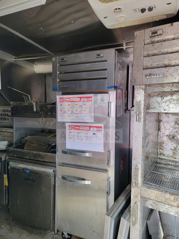 Mobile kitchen interior of 2021 Rock Solid Cargo trailer, showing True refrigeration units with CaptiveAire hood, equipment in used condition.