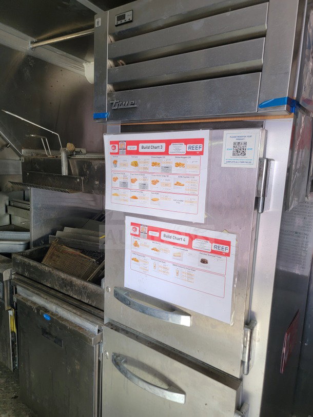 Interior of 2021 Rock Solid cargo trailer showing True refrigeration unit with attached build charts and CaptiveAire hood.