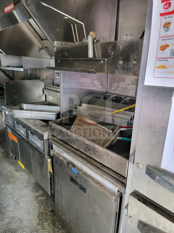 Interior view of 2021 Rock Solid Cargo 8.5' x 24' mobile kitchen trailer featuring CaptiveAire hood, fryers, and refrigeration units.