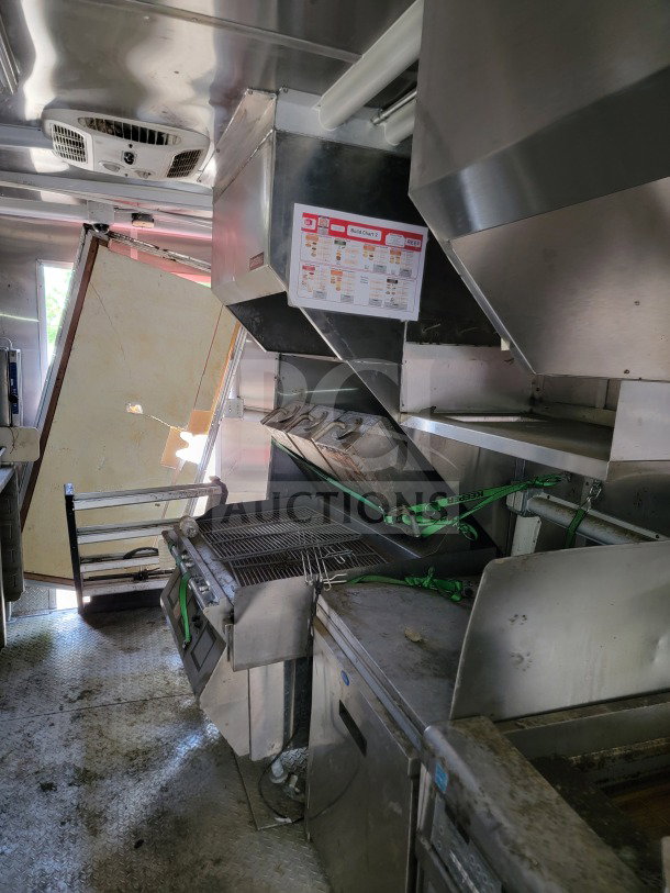 Interior of 2021 Rock Solid Cargo 8.5' x 24' mobile kitchen trailer featuring CaptiveAire hood, grill, and refrigeration units.