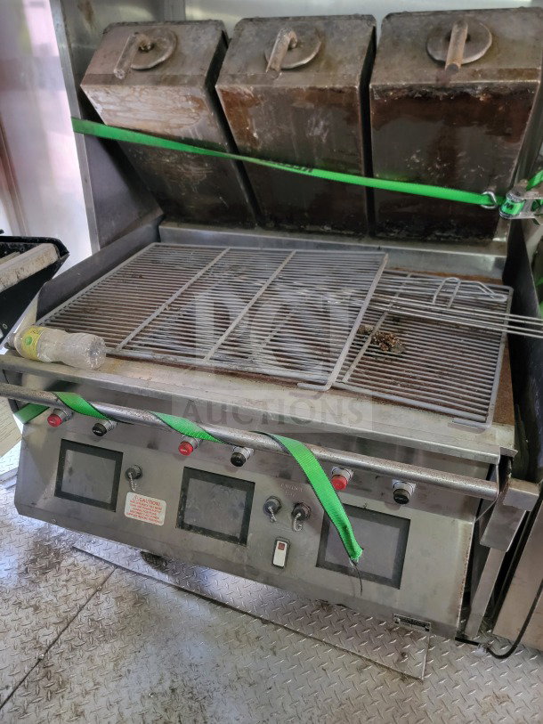 Dual-burner commercial grill inside 2021 Rock Solid mobile kitchen trailer. Worn condition with green strap securing lid.