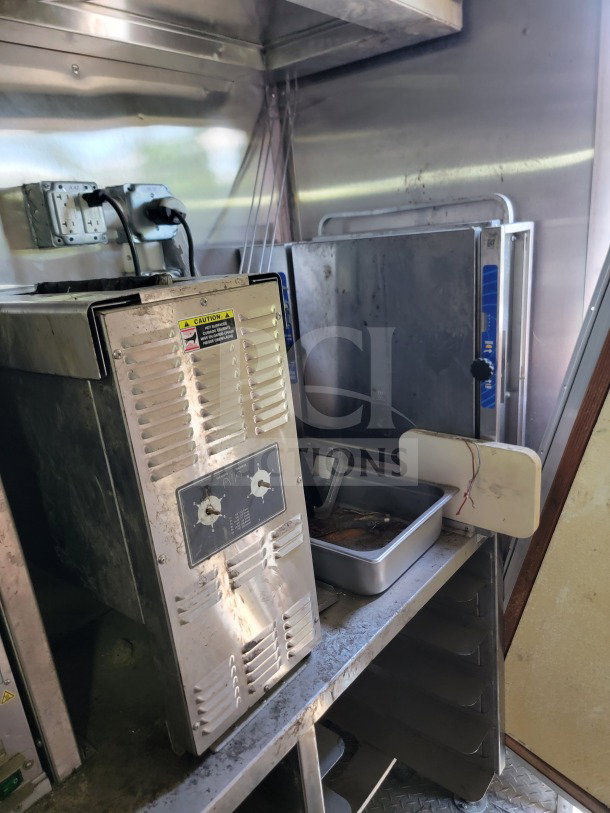 Interior of 2021 Rock Solid Cargo mobile kitchen trailer showing used stainless steel equipment and shelving.