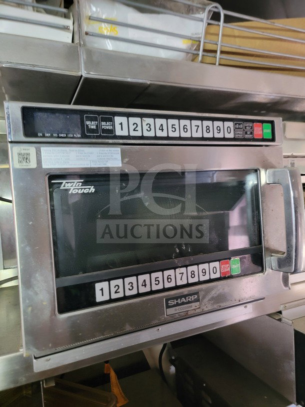 Sharp R-CD2200M microwave with numeric keypad and control buttons, mounted in a mobile kitchen trailer.