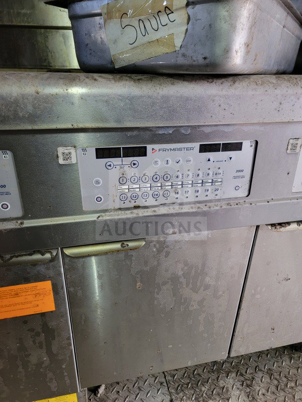 Frymaster control panel in mobile kitchen trailer, showing keypad functions; label reads "Sauce." Worn exterior.