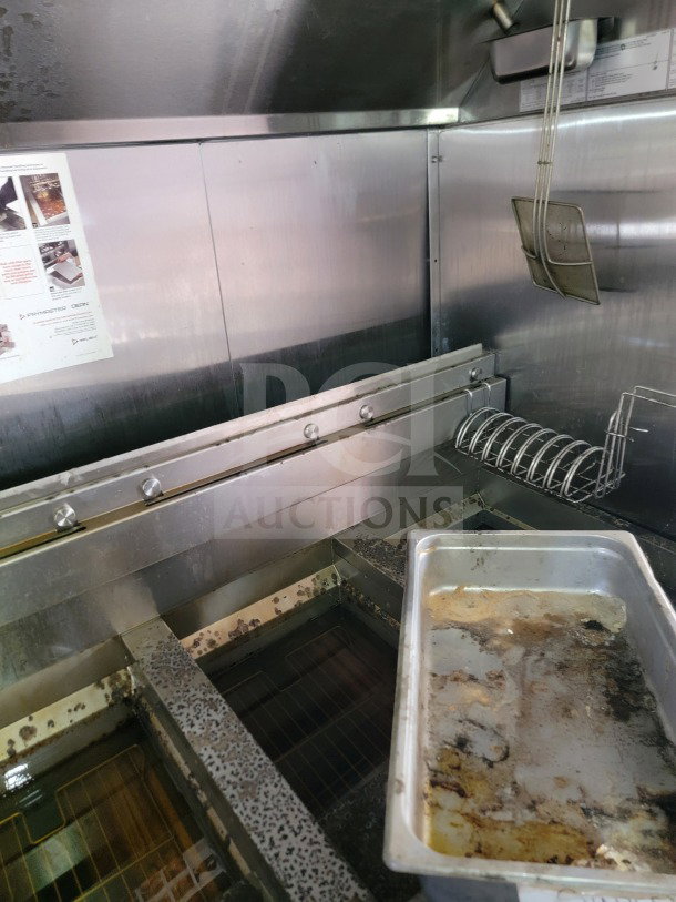 Interior of a Rock Solid Cargo mobile kitchen trailer with a CaptiveAire hood and used fryer area, including a greasy metal tray.
