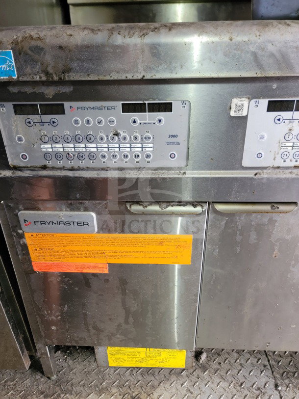Frymaster 3000 fryer controls in a mobile kitchen trailer. Visible wear with caution labels and QR code.