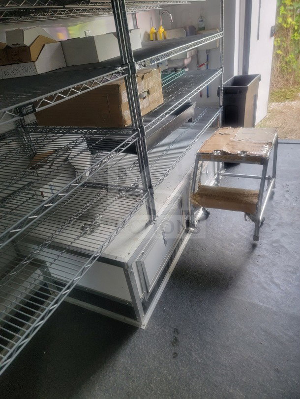 SDG 8.5' x 20' mobile trailer interior with metal shelving, storage boxes, and a stepped stool. Suitable for retail use.