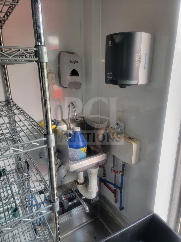 Interior of SDG Model 20 trailer showing a stainless steel sink, Gojo soap dispenser, paper towel holder, and metal shelving.