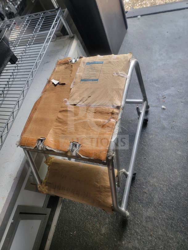 Aluminum cart inside 2021 SDG mobile retail trailer. Cart has taped paper coverings. Shelving visible in background.