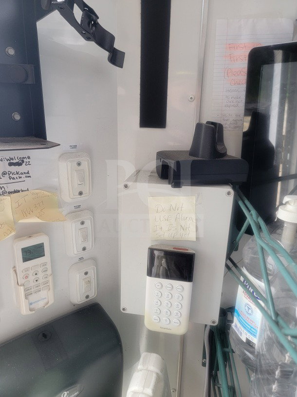 Interior of 2021 SDG 8.5' x 20' trailer showing control panel, alarm keypad with note, and shelving with bottled water.
