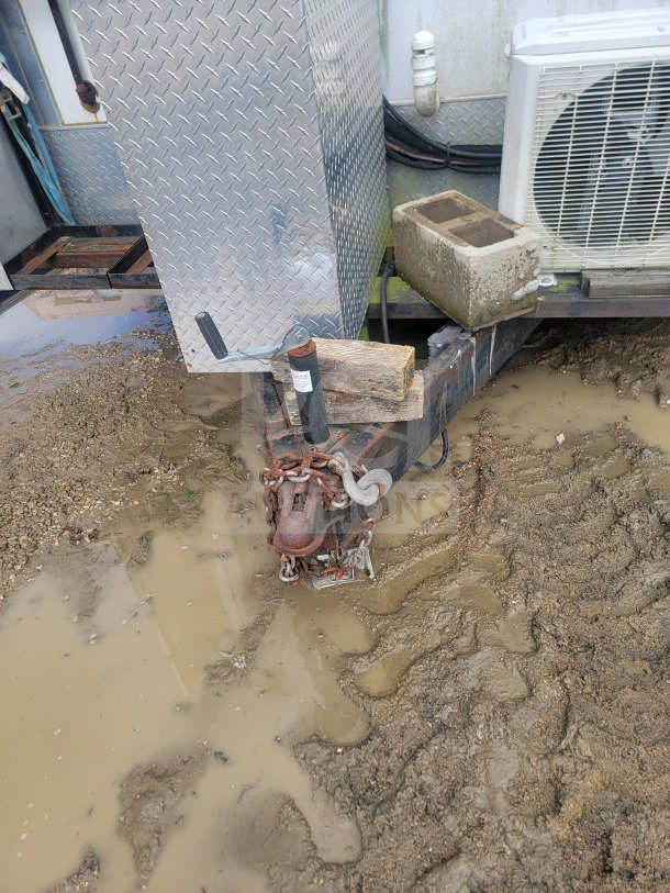 2021 Rock Solid Cargo 8.5' x 24' dual-axle mobile ghost kitchen trailer hitch, showing connections and surrounding mud.