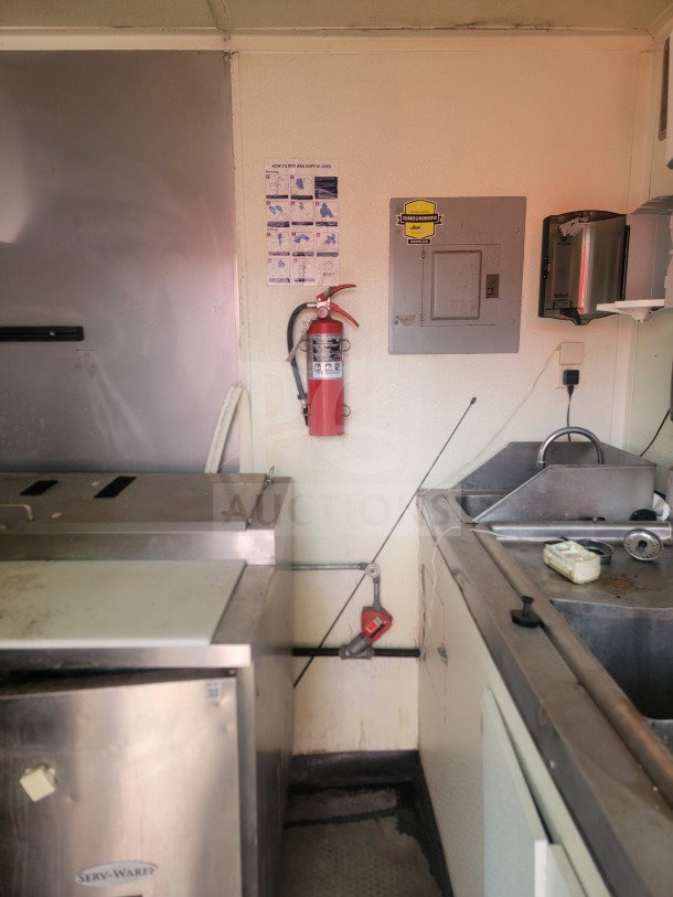 2021 Rock Solid Cargo 8.5' x 24' mobile ghost kitchen interior, featuring Serv-Ware refrigeration, fire extinguisher, and sink unit.