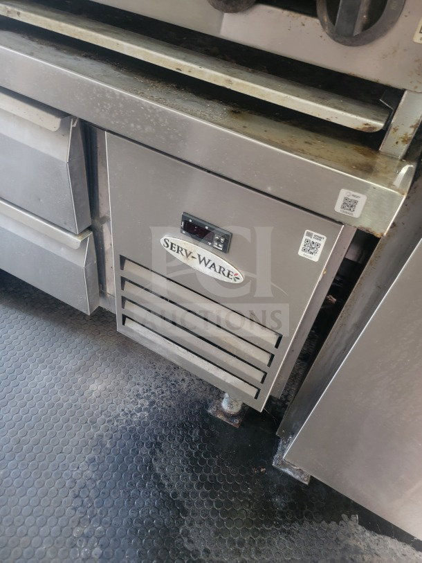 Serv-Ware refrigeration unit in the 2021 Rock Solid Cargo mobile kitchen trailer. Visible wear, Serv-Ware label and QR codes.